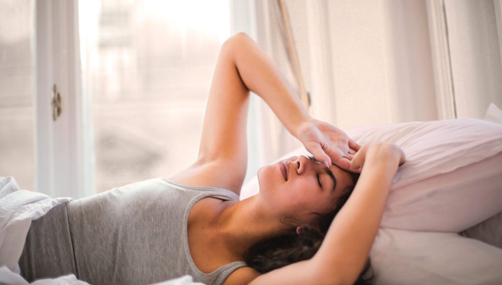 A lady in bed, stretching and looking tired.  Diffuser blends for sleep
